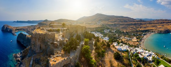 Breathtaking panoramic aerial view of Lindos town from the Acropolis of Lindos in Rhodes, Greece. Amazing colorful sunset scenery in Rhodes. Idyllic background above Aegean sea. Dodecanese, Greece